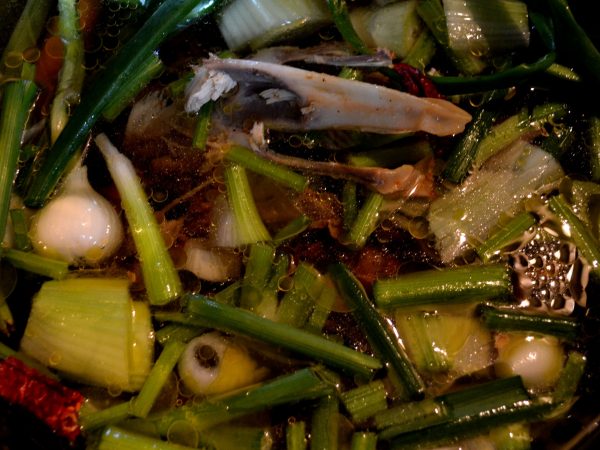 Grönsaker och kycklingrester i en gryta kokas till buljong