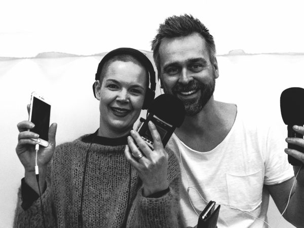 Sara och Johannes i svartvitt fotot, hållandes sina telefoner med diverse sladdar.