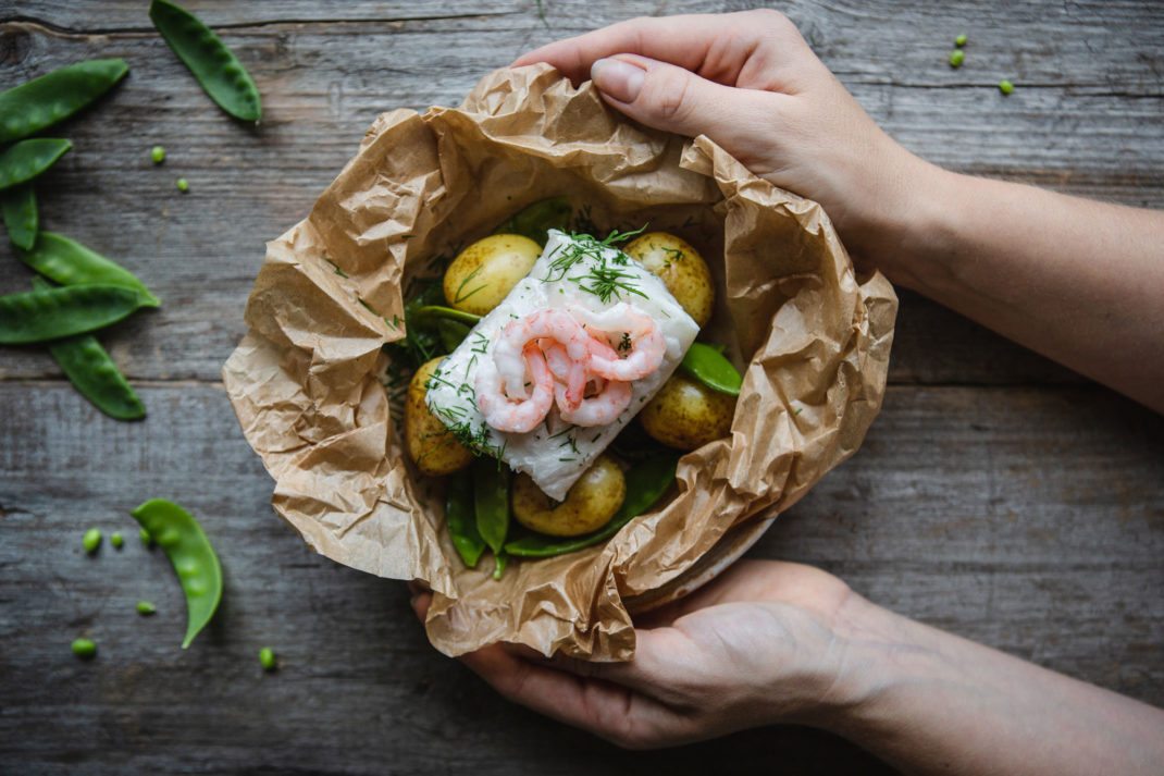 I en knyte av bakplåtspapper ligger gyllengul potatis, krämig, vit fisk och sockerärtor.