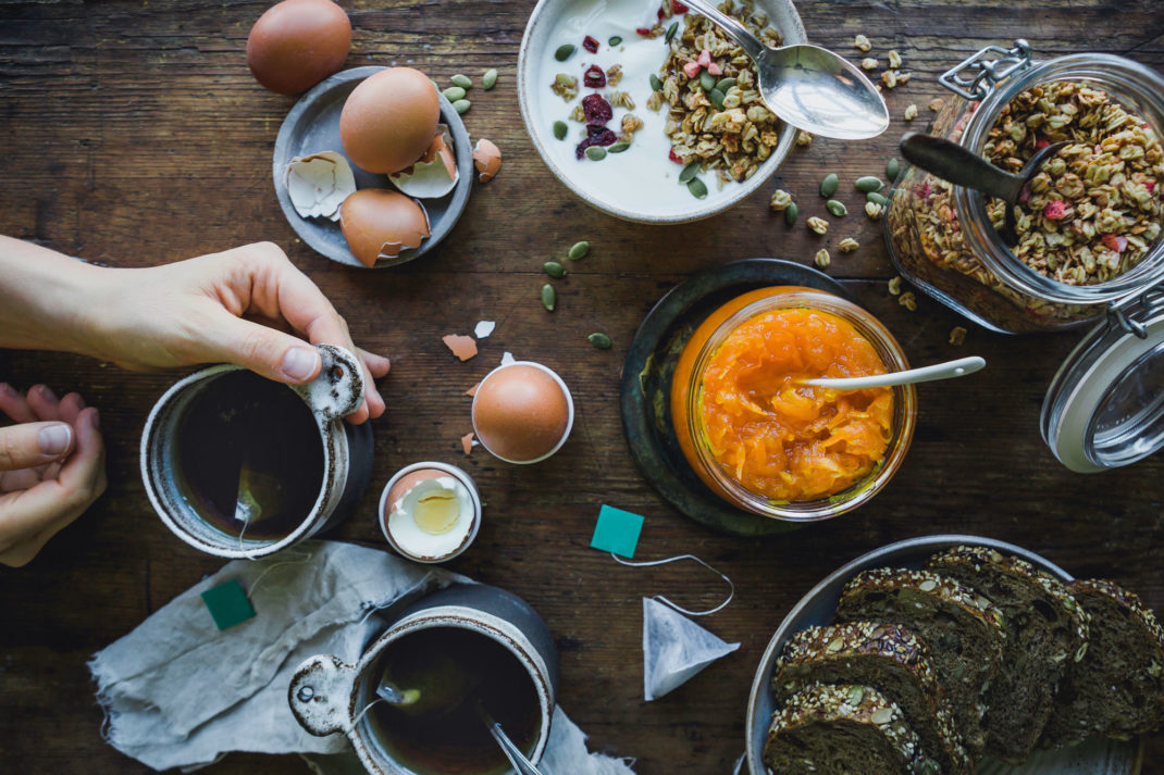 Ett helt frukostbord med mackor, ägg, müsli och morotsmarmelad.