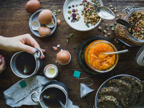 Ett helt frukostbord med mackor, ägg, müsli och morotsmarmelad.