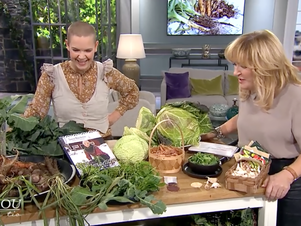 Sara och Malou von Siwerts står vid ett bord med massor av grönsaker på.