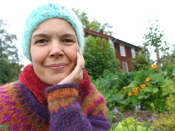 Sara Bäckmo sitter i en sensommarköksträdgård.