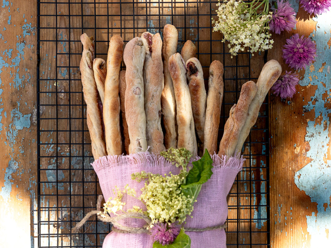 Fina brödpinnar med rabarber och kardemumma i en lila handduk.