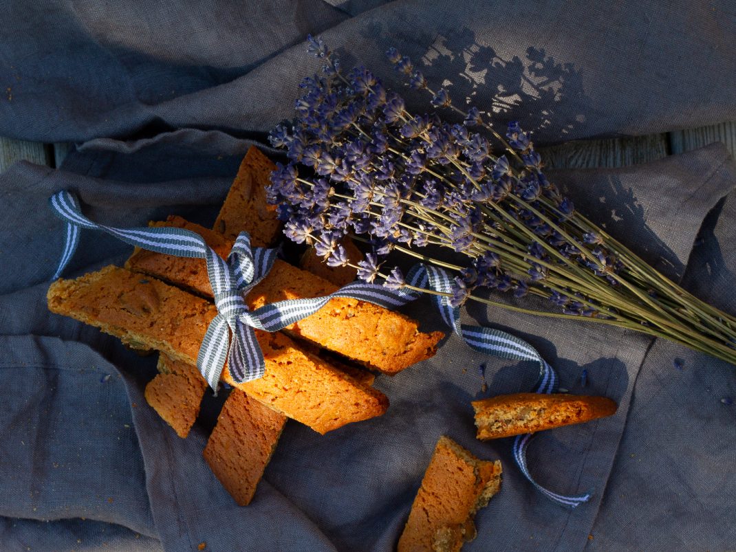 En litet paket av krispiga biscottis med en rosett och en lavendelbukett bredvid.