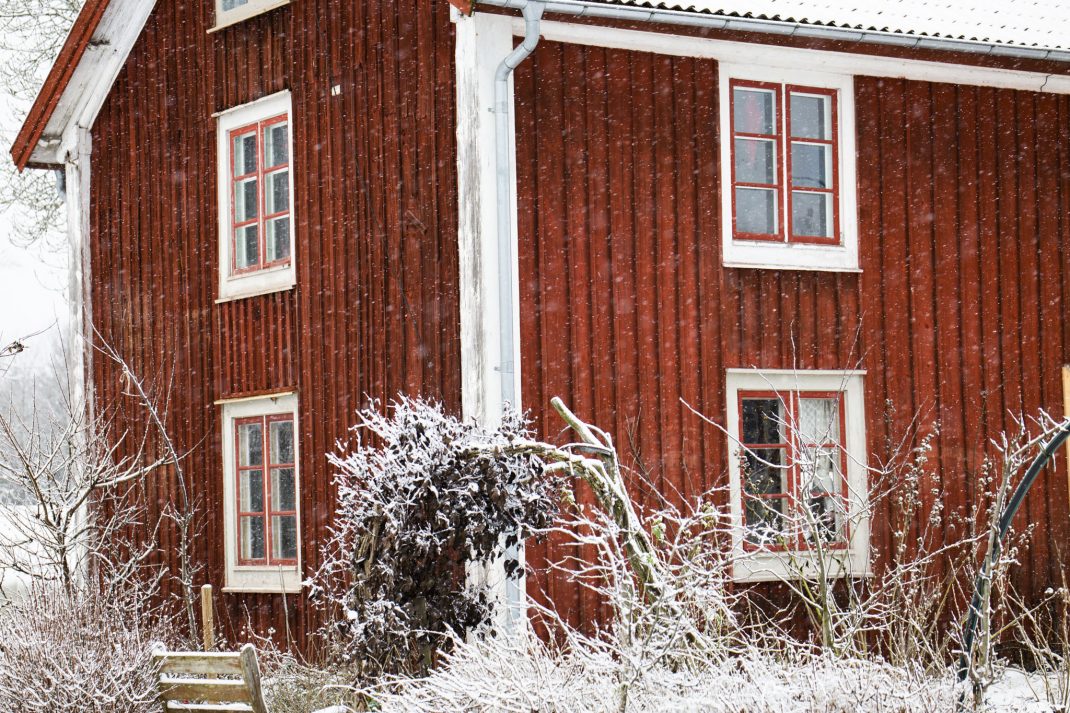 Rött hus i snöfall.