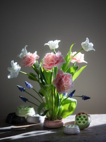 En vacker bukett med tulpaner och blå pärlhyacinterstår fint i en blomhållare i keramik..
